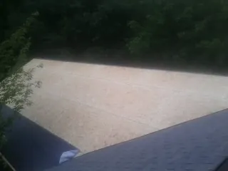 New OSB roof sheathing installed beside an existing shingle roof in Epsom