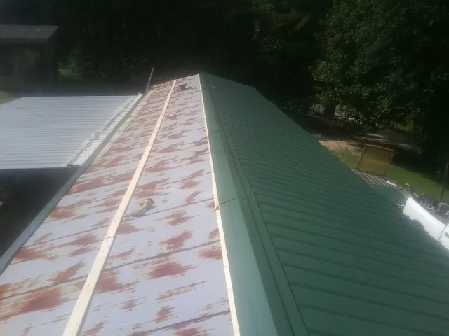 Old rusted panels beside newly installed green metal roofing — Wind Damage Roof Repair by Roofing Brothers in Epsom