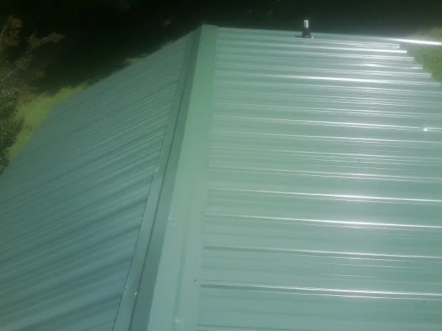 New green metal panels meeting at the ridge of a roof — Flat Roof Repair work by our crew in Epsom