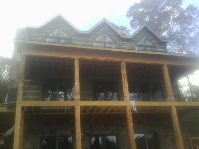 Dormers and porch framing on a large log home under construction — Roof Coating work by our crew in Epsom