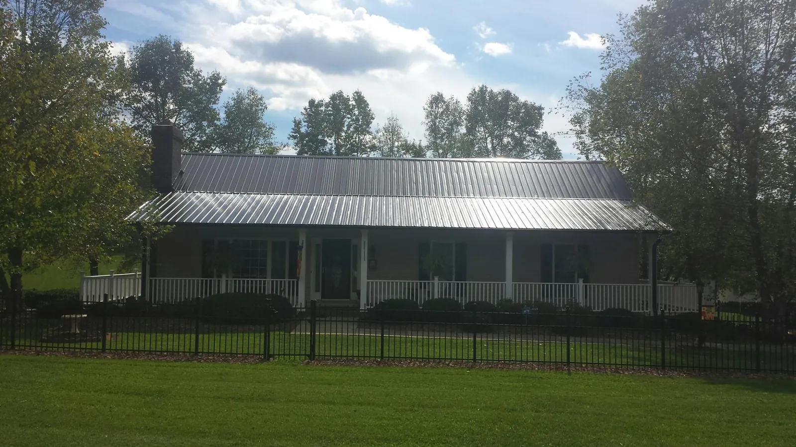 Gray metal roof on a brick ranch with a full width front porch — Gutter Guard Installation work by our crew in Epsom