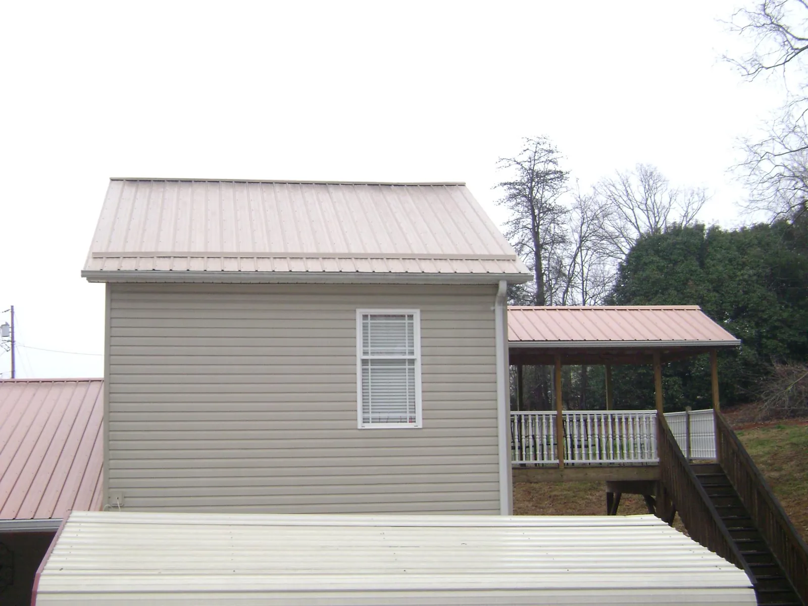 Tan metal roofs on a two story addition and attached porch, from a Roof Replacement job in Epsom