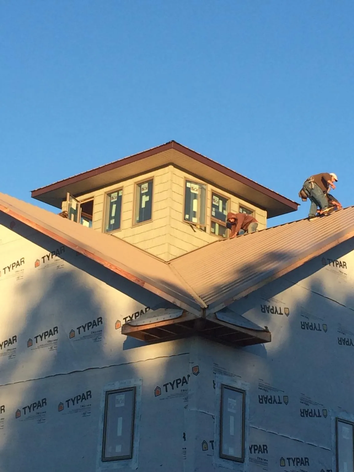 Roofers working around a rooftop cupola on a new metal roof at sunset — Roof Waterproofing in Epsom by Roofing Brothers